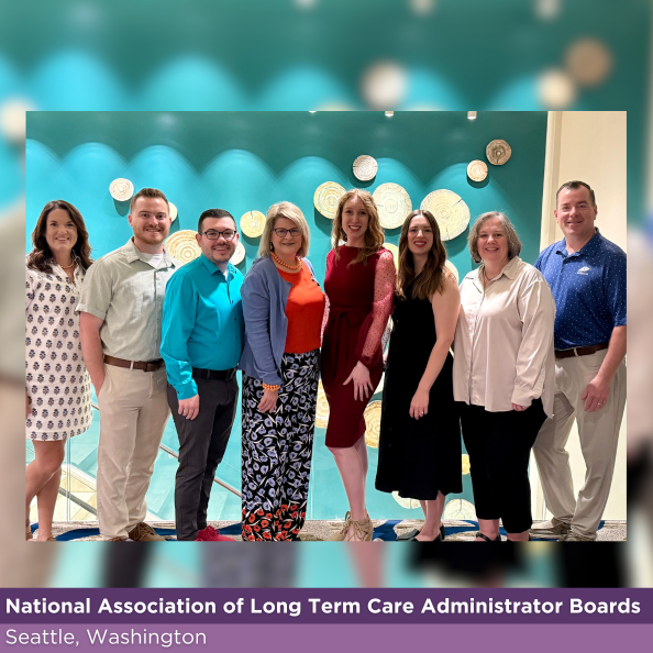 Group of eight people standing in front of teal and white wall.